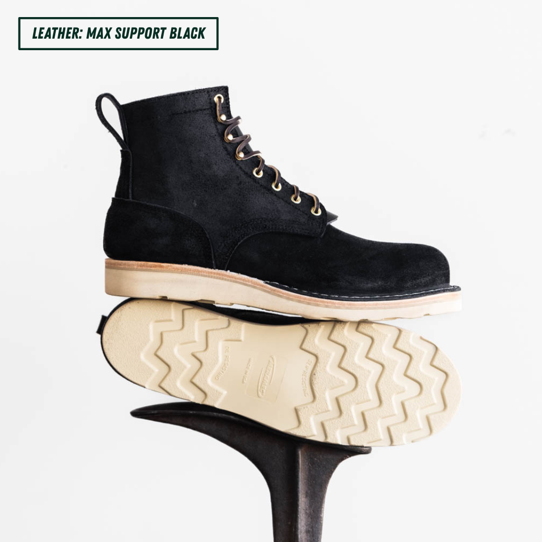 Short black boots, one is laying down on boot jack showing the outsole while the other is showing side profile sitting on top the other. Top left reads "LEATHER: MAX SUPPORT BLACK."