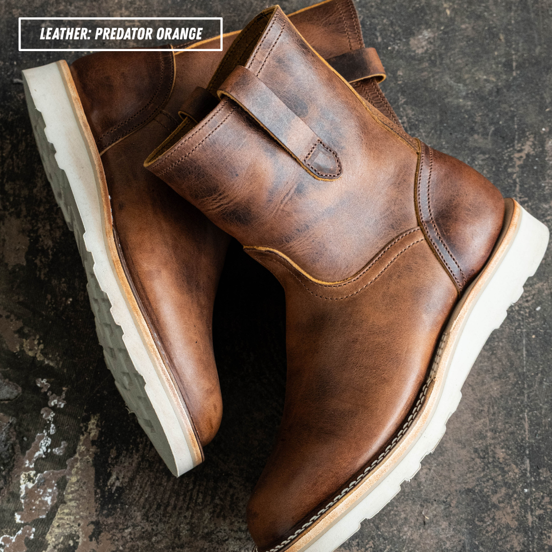 A pair of distressed leather ankle boots in a rich brown shade, featuring a pull strap and thick white lug soles, displayed on a dark textured surface with a text overlay in the top left corner.