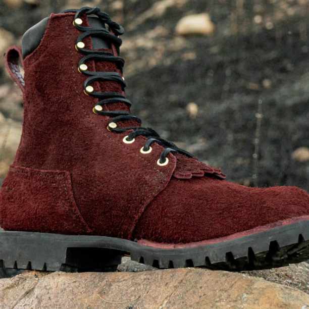 Red boot with black sole on a rock against a natural background
