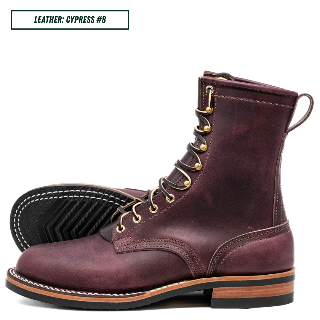 A pair of lace-up ankle boots in distressed plum cypress leather, shown on a white background with one boot standing upright and the other lying on its side to display the sole. A text label in the top left reads 'LEATHER: CYPRESS #8'.