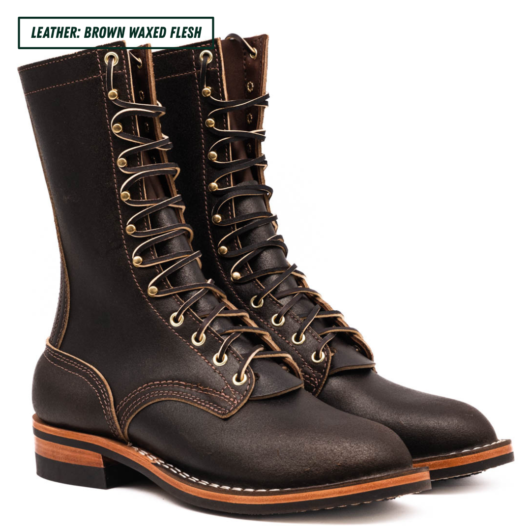 A pair of dark brown waxed leather lace-up boots with brass eyelets and white contrast stitching, shown on a white background with a text label in the top left corner.