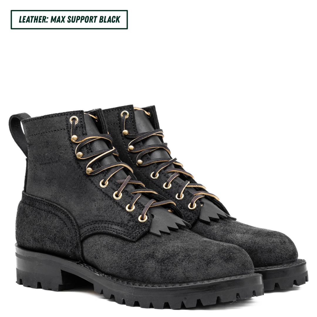 Pair of black suede boots with gold laces on a white background