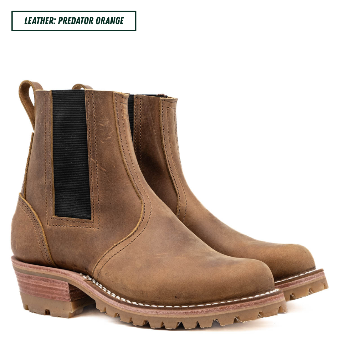 A pair of distressed brown leather Chelsea boots with black elastic side panels and chunky lug soles, shown on a white background with a text label reading 'LEATHER: PREDATOR ORANGE'.