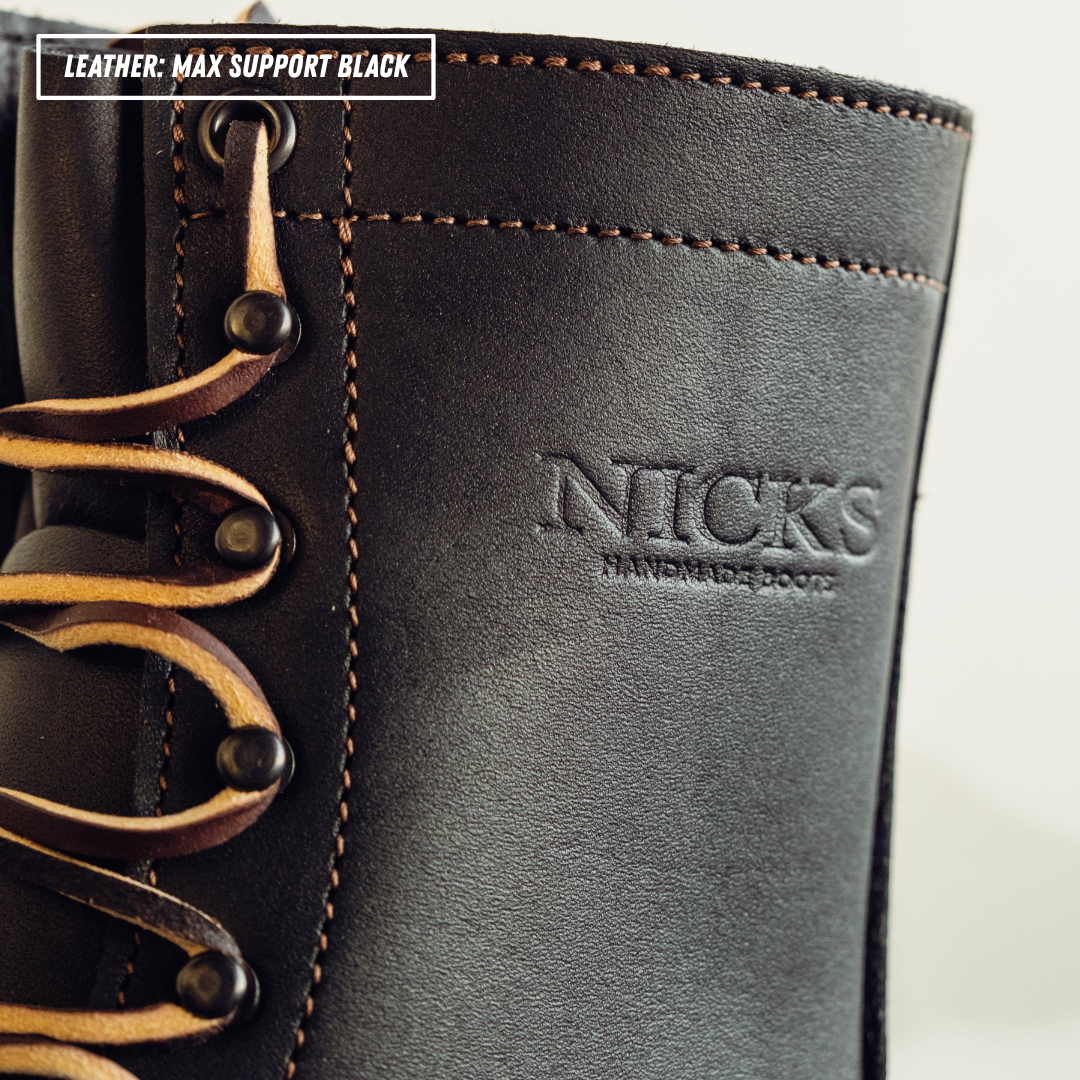 Close-up of a black leather boot with tan laces and visible 'NICKS HANDMADE BOOTS' branding on the side, plus a text label reading 'LEATHER: MAX SUPPORT BLACK'.