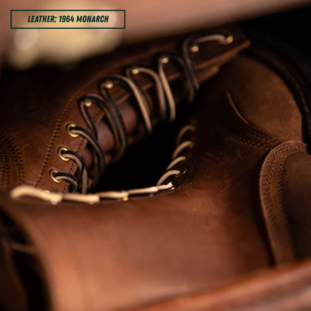 Close-up of a brown leather lace-up boot with metal eyelets and dark laces, with a text label in the top-left corner reading 'LEATHER: 1964 MONARCH'.