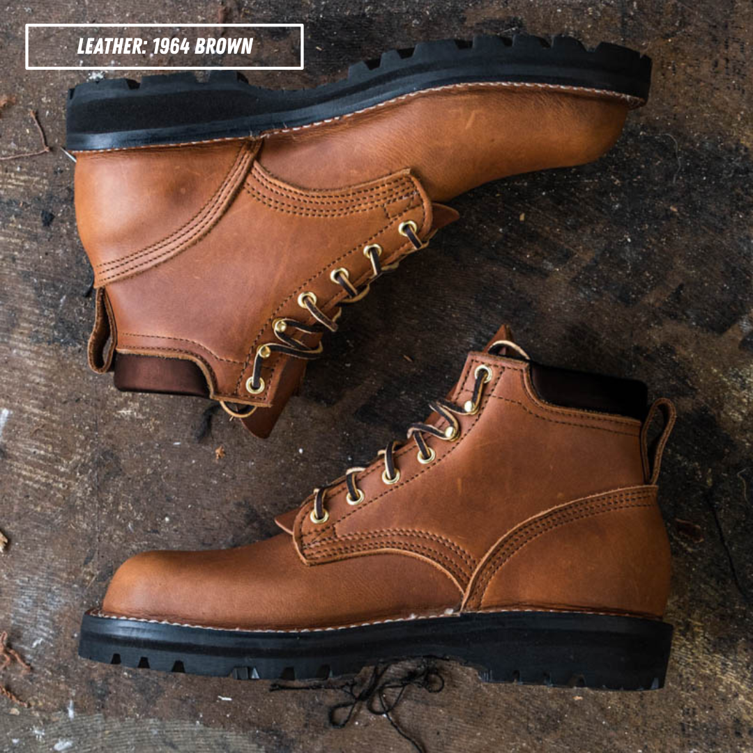 A pair of rugged lace-up work boots in leather, shown from top and side angles on a dark rustic wooden surface. A text overlay in the top left reads 'LEATHER: 1964 BROWN'.