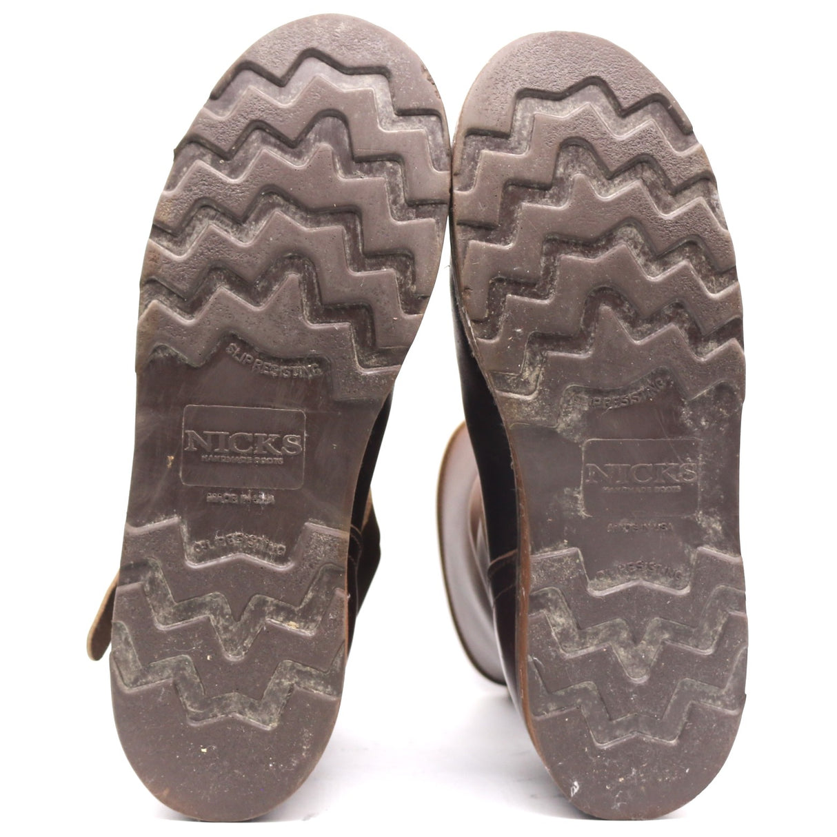 The soles of a pair of boots, showing the zig-zag tread pattern and the embossed brand name 'NICKS'.