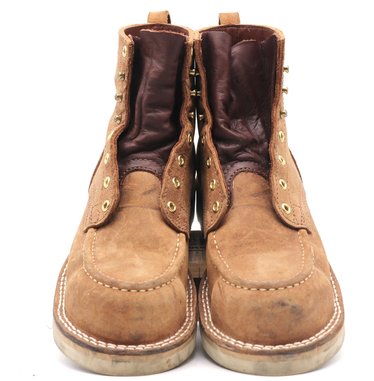 A pair of rugged brown leather lace-up boots with gold-tone eyelets and white contrast stitching, photographed against a plain white background.