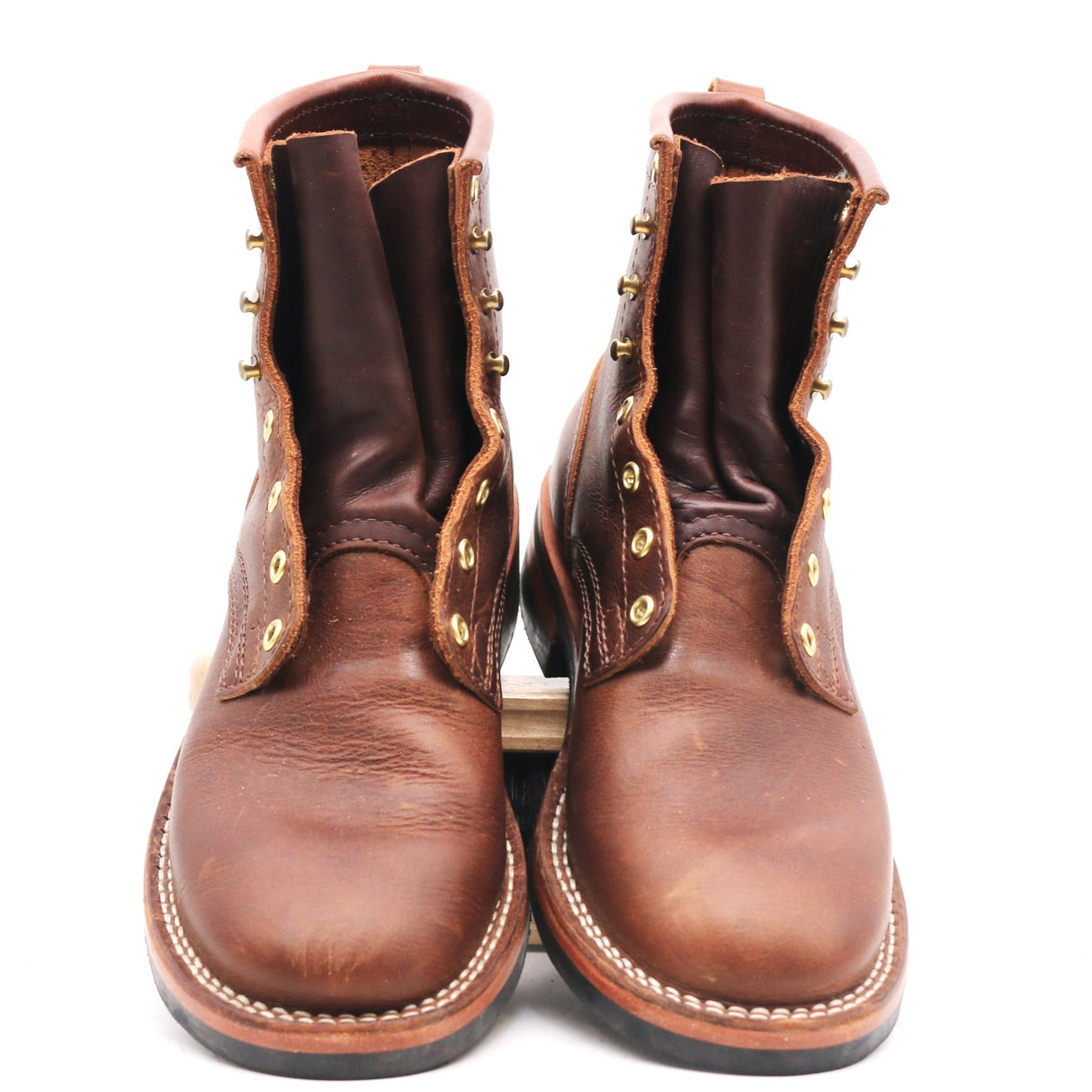 A pair of brown leather lace-up ankle boots with brass eyelets and white contrast stitching, photographed against a plain white background.