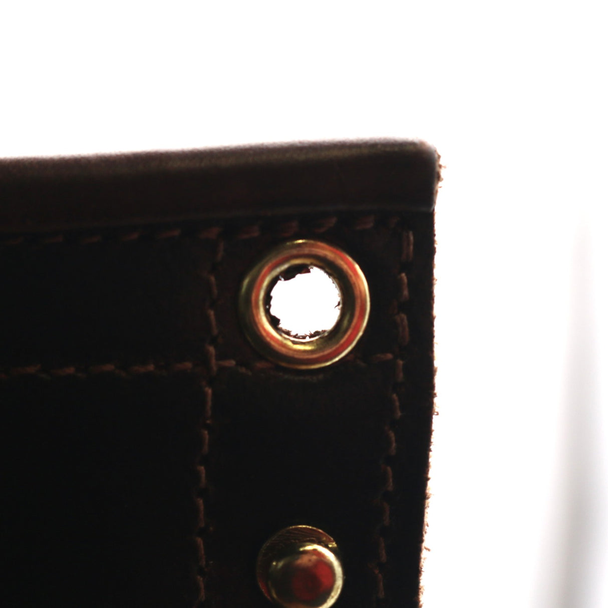 Up close photo of damaged top brass eyelet on a pair of boots.