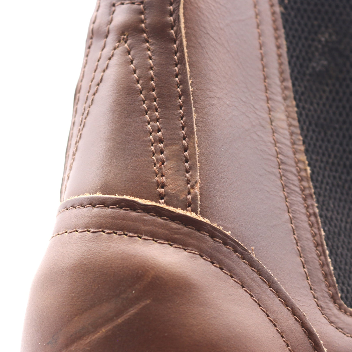 Close up of a two-piece brown leather boot backstay showing visible scuff marks.
