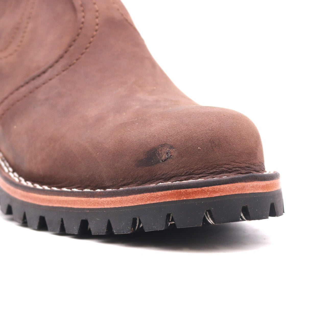 Close-up of a brown leather boot showing the toe cap, stitching, and a black lug sole against a white background.