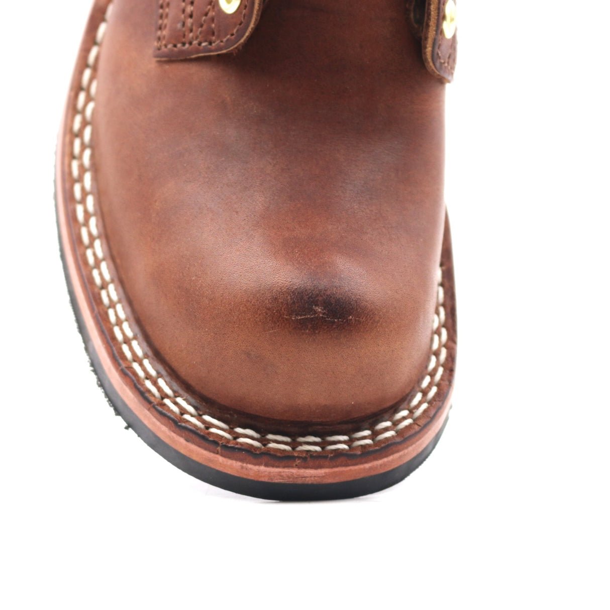 Close up image of the right toe of a brown leather boot. Visible crack in the leather on the toe.