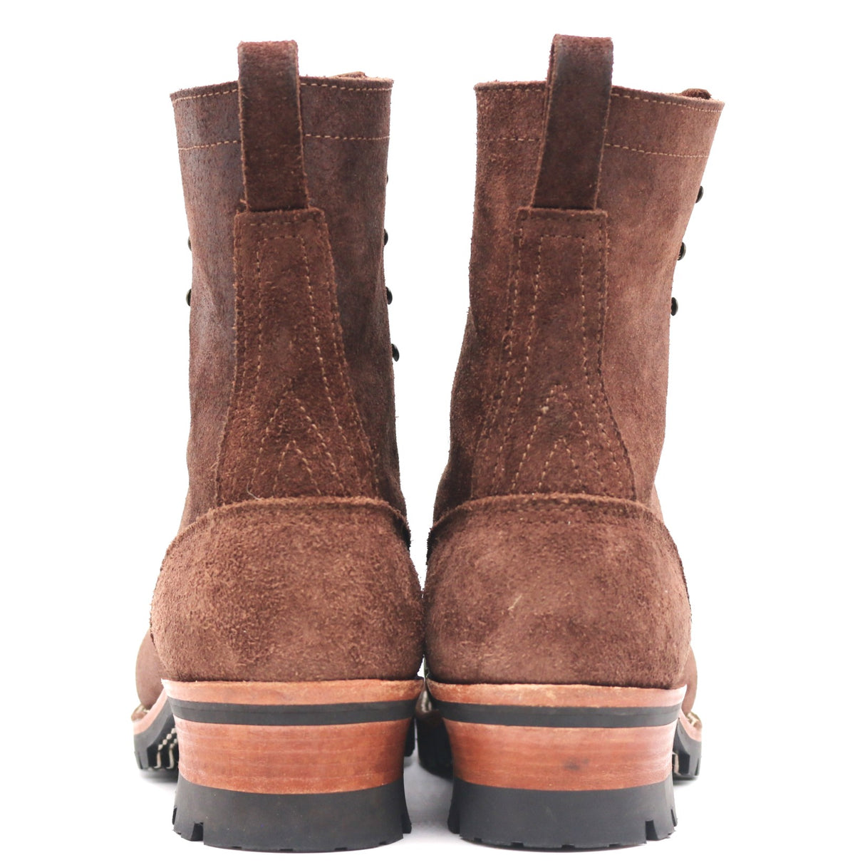 A pair of brown suede lace-up boots shown from the back, featuring a stacked sole with a black rubber toe and heel, and a light brown wood-toned midsole.