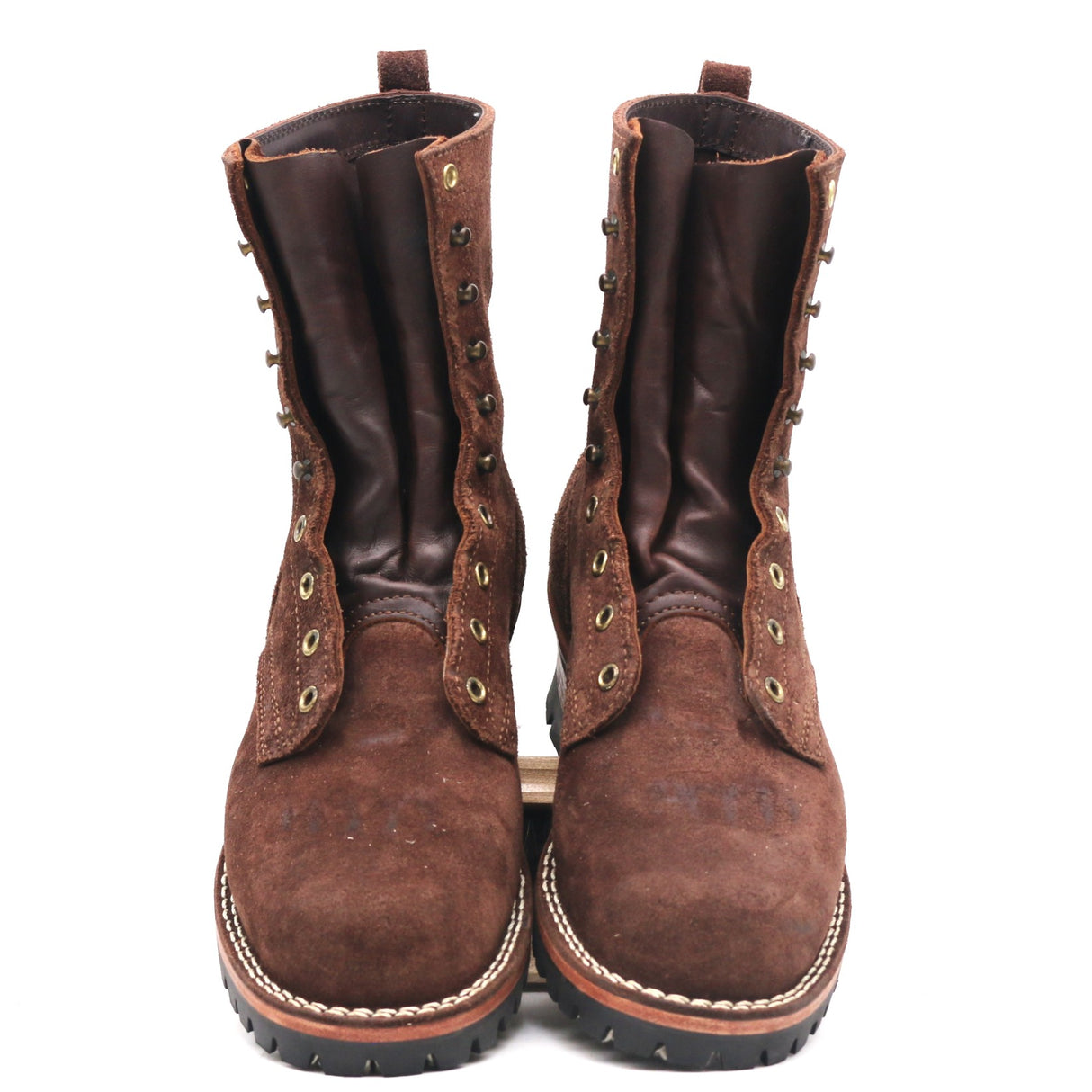 A pair of brown suede and leather lace-up boots with metal eyelets and pull tabs, shown from the front on a white background.
