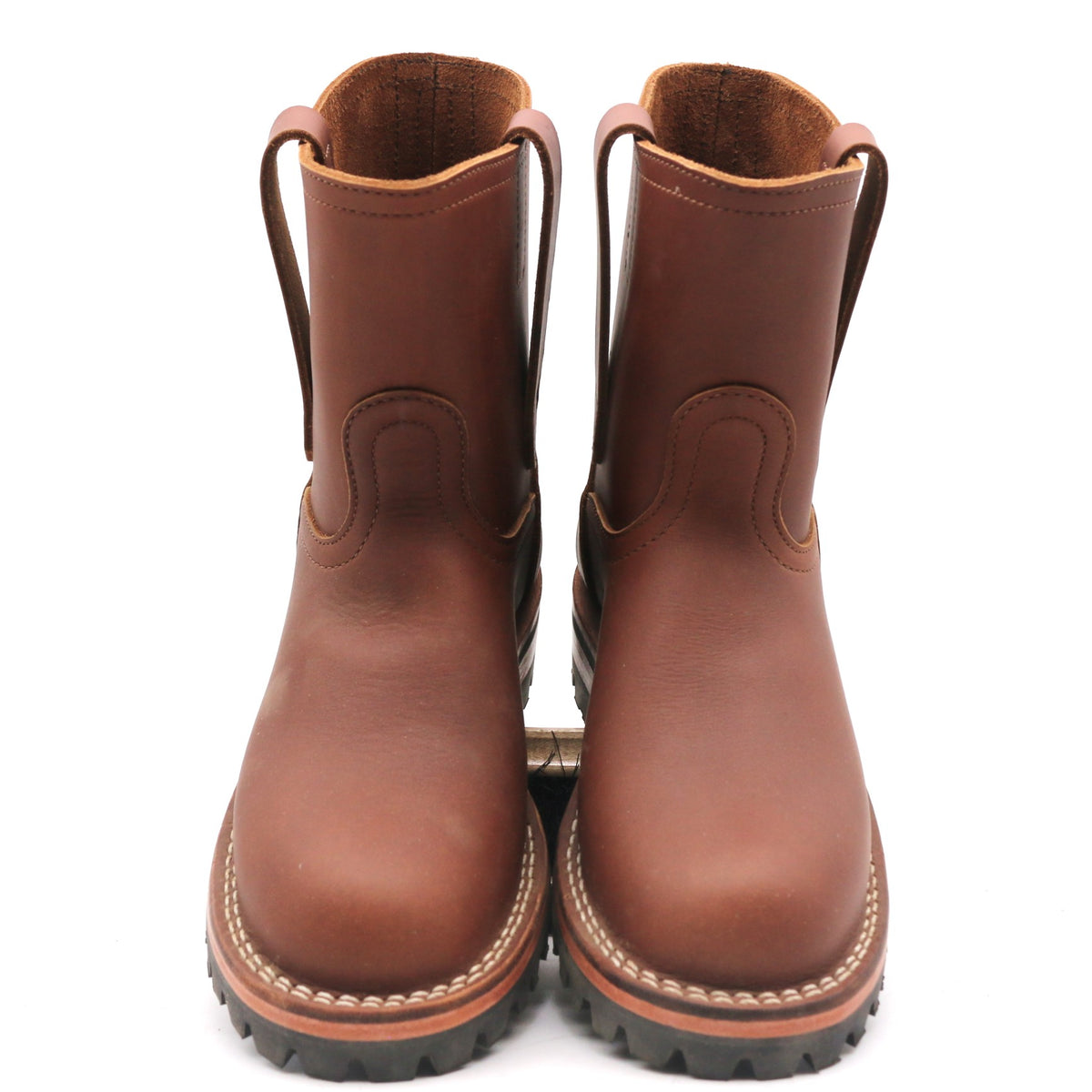 A pair of brown leather mid-calf boots with pull tabs and thick black lug soles, shown from a front-facing perspective on a white background.
