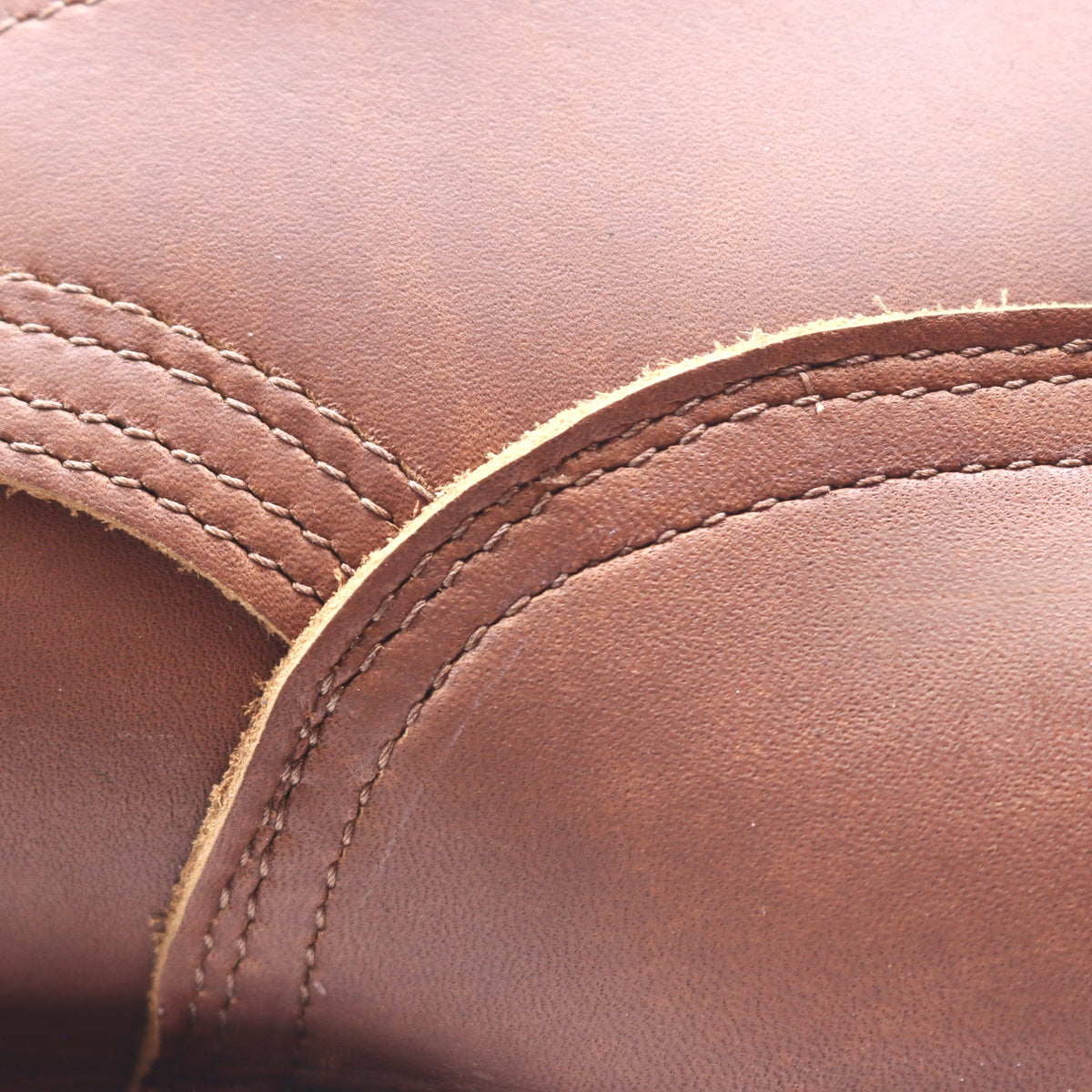 Close up of the heel counter of a brown leather boot. Image shows uneven sewing along the edges.