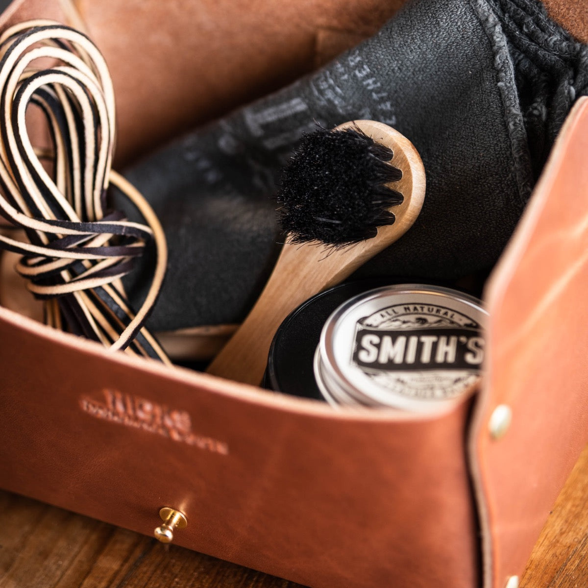 Leather Box filled with brush, rag, leather laces, and leather care brush.