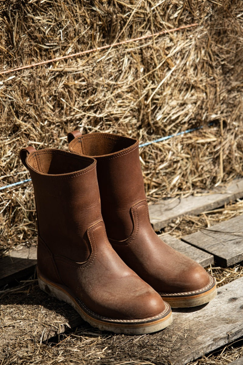 Brown wellington chore boot in a barn. The perfect boot to keep by your door