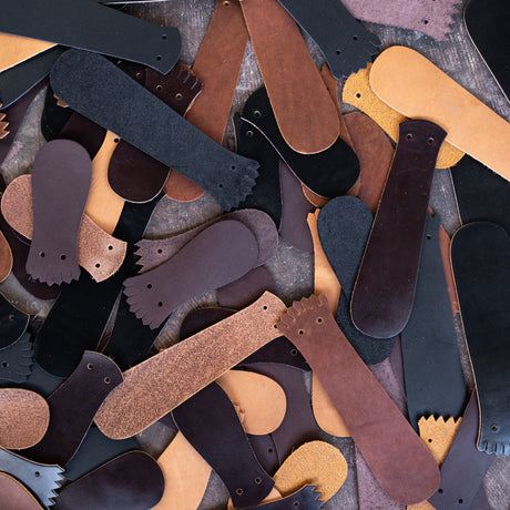 A pile of different leather kilties laying on the ground. 