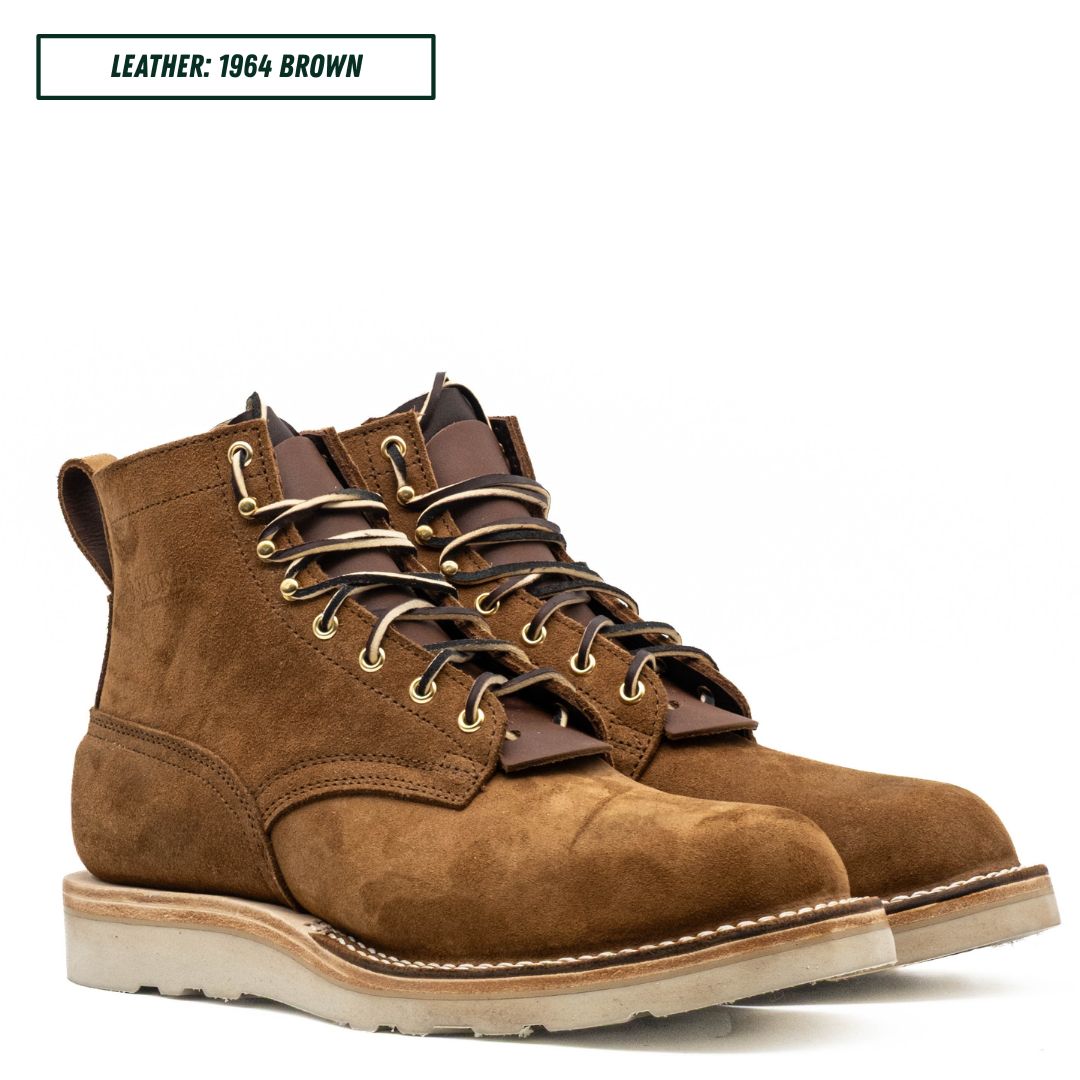 A pair of brown suede lace-up work boots shown on a white background with a text label in the top left that reads 'LEATHER: 1964 BROWN'.