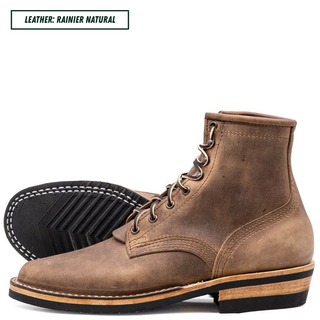 A pair of rainier natural brown leather lace-up ankle boots, with one boot standing upright and the other lying on its side to show the treaded black outsole. A text label in the top left corner reads 'LEATHER: RAINIER NATURAL'.