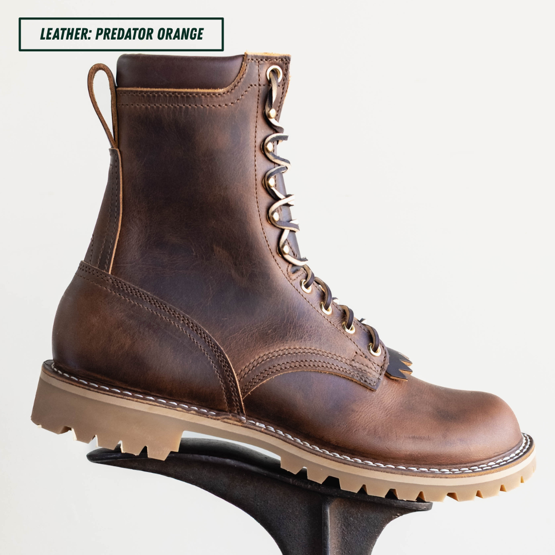 A single lace-up ankle boot in distressed brown leather with a tan rubber sole, shown on a display stand against a light gray background. A text label in the top left reads 'LEATHER: PREDATOR ORANGE'.