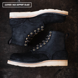 Short black boots laying on textured concrete. Top left reads "LEATHER: MAX SUPPORT BLACK."