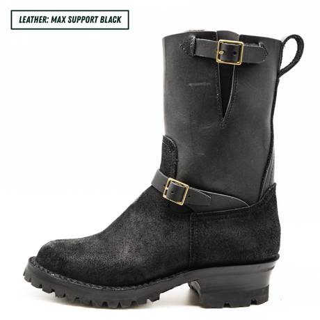 A black leather and suede mid-calf boot with gold-tone buckle details, a pull loop, and a rugged lug sole, shown against a plain white background with a text label in the top-left corner.