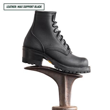 A black leather lace-up boot with a chunky lug sole and block heel, displayed on a metal shoe stand against a white background. A text label in the top-left corner reads 'LEATHER: MAX SUPPORT BLACK'.