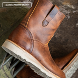 A close-up of a brown leather ankle boot with a pull tab, shown on a dark textured surface. A text overlay in the top left reads 'LEATHER: PREDATOR ORANGE'.