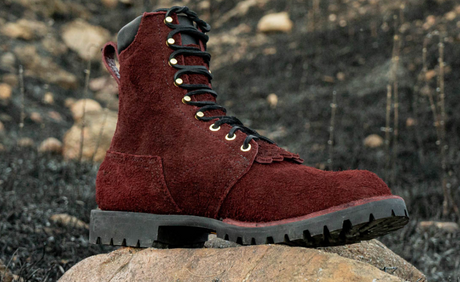 Red boot with black sole on a rock against a natural background