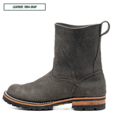 A single dark gray suede ankle boot shown in side profile on a white background, with a small text label in the top left reading 'LEATHER: 1964 GRAY'. The boot has a pull loop at the back, a rugged black lug sole, and a tan midsole layer.