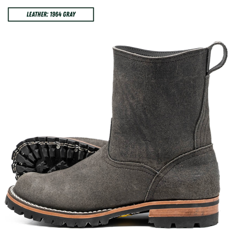 A dark gray suede ankle boot shown in side profile with a second boot placed behind it to show the sole. A text label in the top left reads 'LEATHER: 1964 GRAY'.