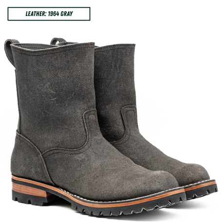 A pair of dark gray leather ankle boots with rugged lug soles and a tan midsole, shown on a white background with a text label reading 'LEATHER: 1964 GRAY'.