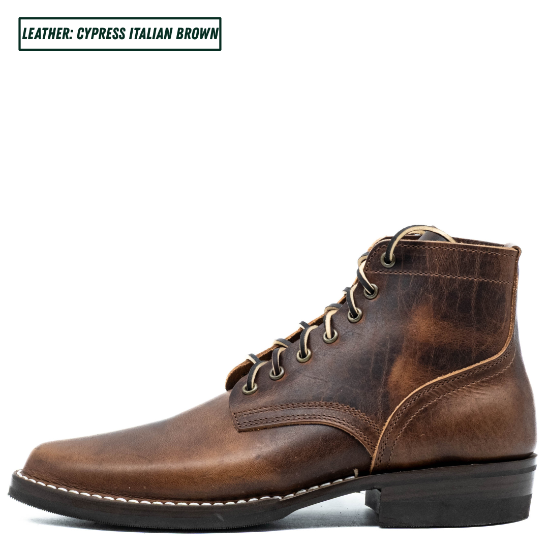 A single distressed leather ankle boot in a rich brown shade, featuring tan laces, metal eyelets, and white contrast stitching. A text overlay in the top left corner reads 'LEATHER: CYPRESS ITALIAN BROWN'.
