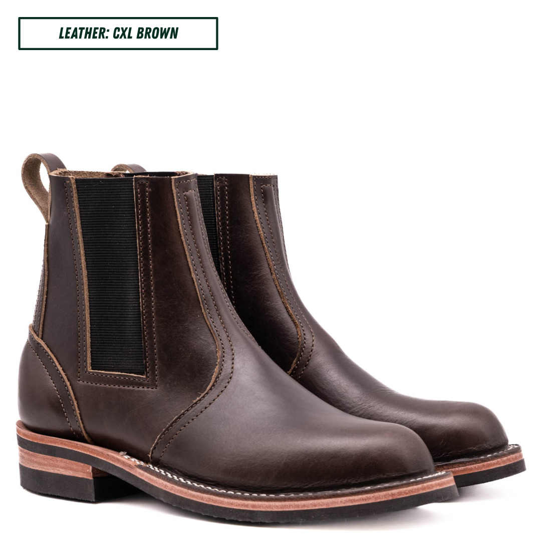 A pair of dark brown leather Chelsea boots with black elastic side panels, shown on a white background with a text label in the top left corner that reads 'LEATHER: CXL BROWN'.