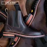 A dark brown leather Chelsea boot with elastic side panels and a stacked sole, shown among other brown boots. A text overlay in the top left reads 'LEATHER: CXL BROWN'.