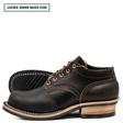 A pair of men's lace-up work boots in dark brown waxed leather, shown from a side profile view with one boot standing upright and the other lying flat to display the sole. The boots feature contrast stitching, a stacked wood-look heel, and a black rubber outsole.