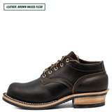 A single dark brown leather lace-up boot shown in side profile on a white background, with a text label in the top-left corner reading 'LEATHER: BROWN WAXED FLESH'. The boot has tan stitching, a stacked wood-look heel, and a black outsole.