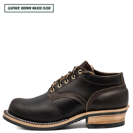 A single dark brown leather lace-up boot shown in side profile on a white background, with a text label in the top-left corner reading 'LEATHER: BROWN WAXED FLESH'. The boot has tan stitching, a stacked wood-look heel, and a black outsole.