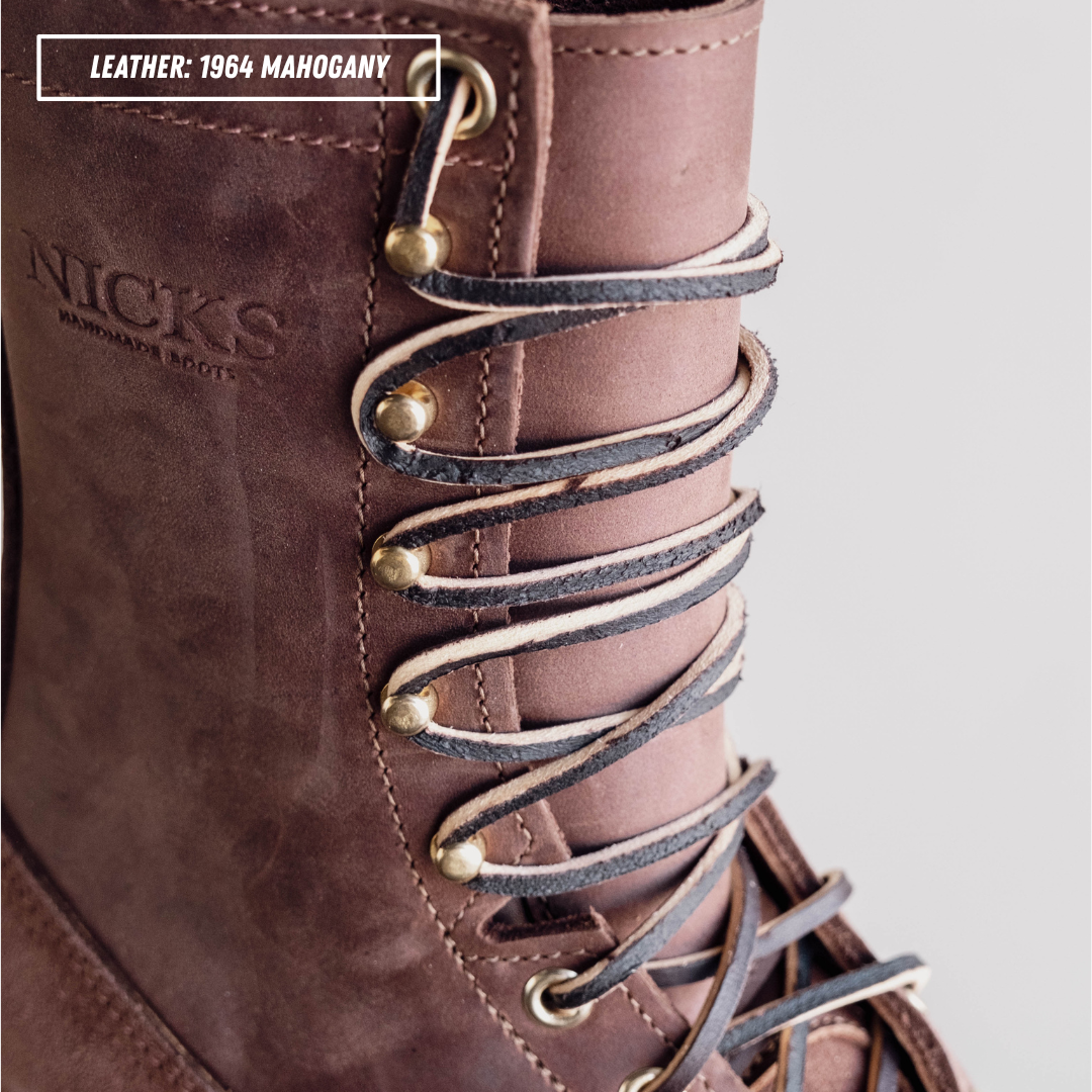 Close-up of a brown leather lace-up boot with dark brown and off-white laces threaded through brass eyelets. The embossed brand name 'NICKS' is visible on the side, and a text label reads 'LEATHER: 1964 MAHOGANY'.