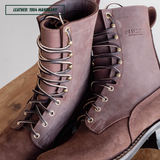 A pair of Nicks leather lace-up boots in a dusty mauve-brown shade, displayed on a wooden surface with a white background.
