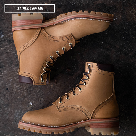 A pair of tan leather lace-up boots arranged on a dark textured surface. One boot is shown from a top-down view and the other from a side angle.