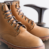 A pair of tan leather lace-up boots photographed close-up on a dark surface with a blurred dark object in the background. A small text overlay in the top left reads 'LEATHER 1964 TAN'.