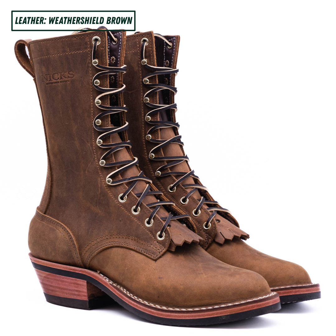 A pair of brown leather lace-up boots with a rugged low block heel, stacked design, and decorative tassel detail on the front, shown against a plain white background with a text label in the top left corner.
