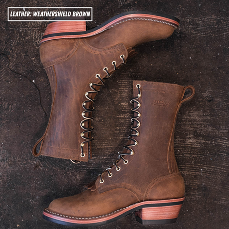 Two brown leather lace-up boots arranged on a dark rustic wooden surface, with a text label in the top-left reading 'LEATHER: WEATHERSHIELD BROWN'. The boots have metal eyelets, pull tabs, and stacked wooden heels.