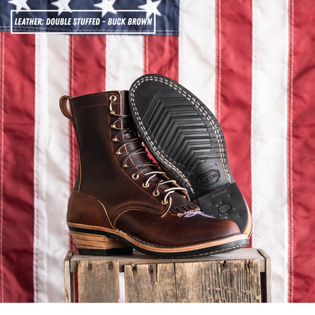 A brown double-stuffed leather lace-up boot with a stacked wood-look heel, shown in profile with an American flag background. A text label in the top-left corner reads 'LEATHER: DOUBLE STUFFED - BUCK BROWN'.