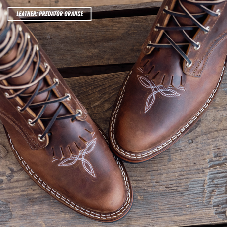 A brown leather packer boot with toe bug detailing. Text label in the top-left corner that reads 'LEATHER: PREDATOR ORANGE'.
