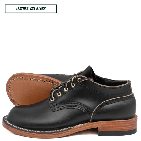 A pair of black leather lace-up shoes shown on a white background, with one shoe standing upright and the other lying on its side to display the tan sole edge and stitching. A small label in the top left reads 'LEATHER: CXL BLACK'.